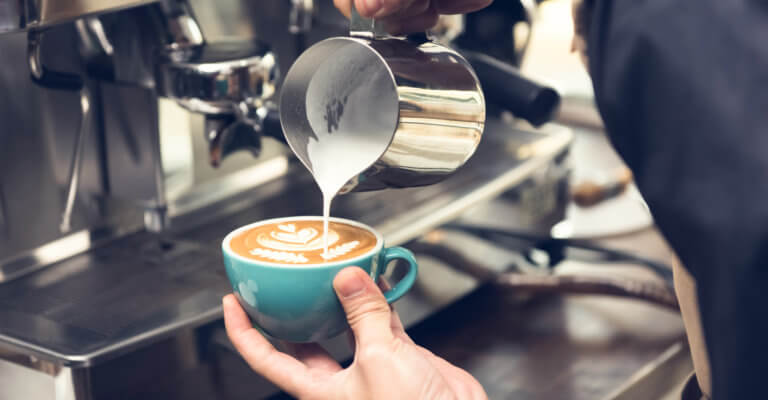 A photo of a person pouring milk into a cup of tea or coffee